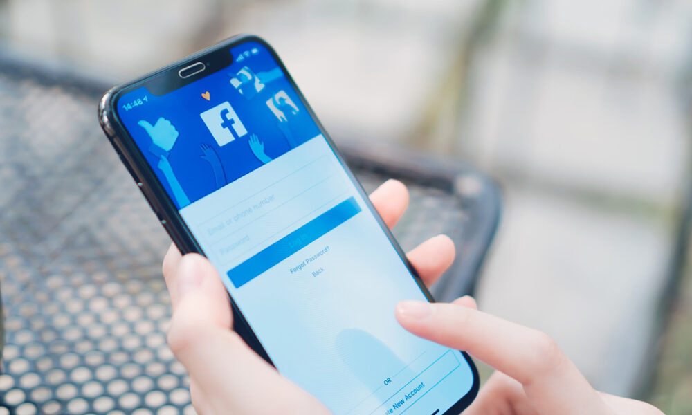 Smartphone u ruci prikazuje Facebook na ekranu